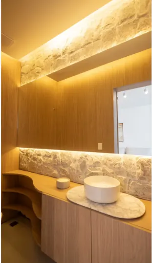 Lavabo com bancada orgânica e painel de ônix retroiluminado